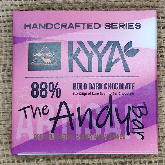 A chocolate bar packaging with 'HANDCRAFTED SERIES KYA 88% BOLD DARK CHOCOLATE The Andy Bar' text on it, placed on a burlap fabric background.